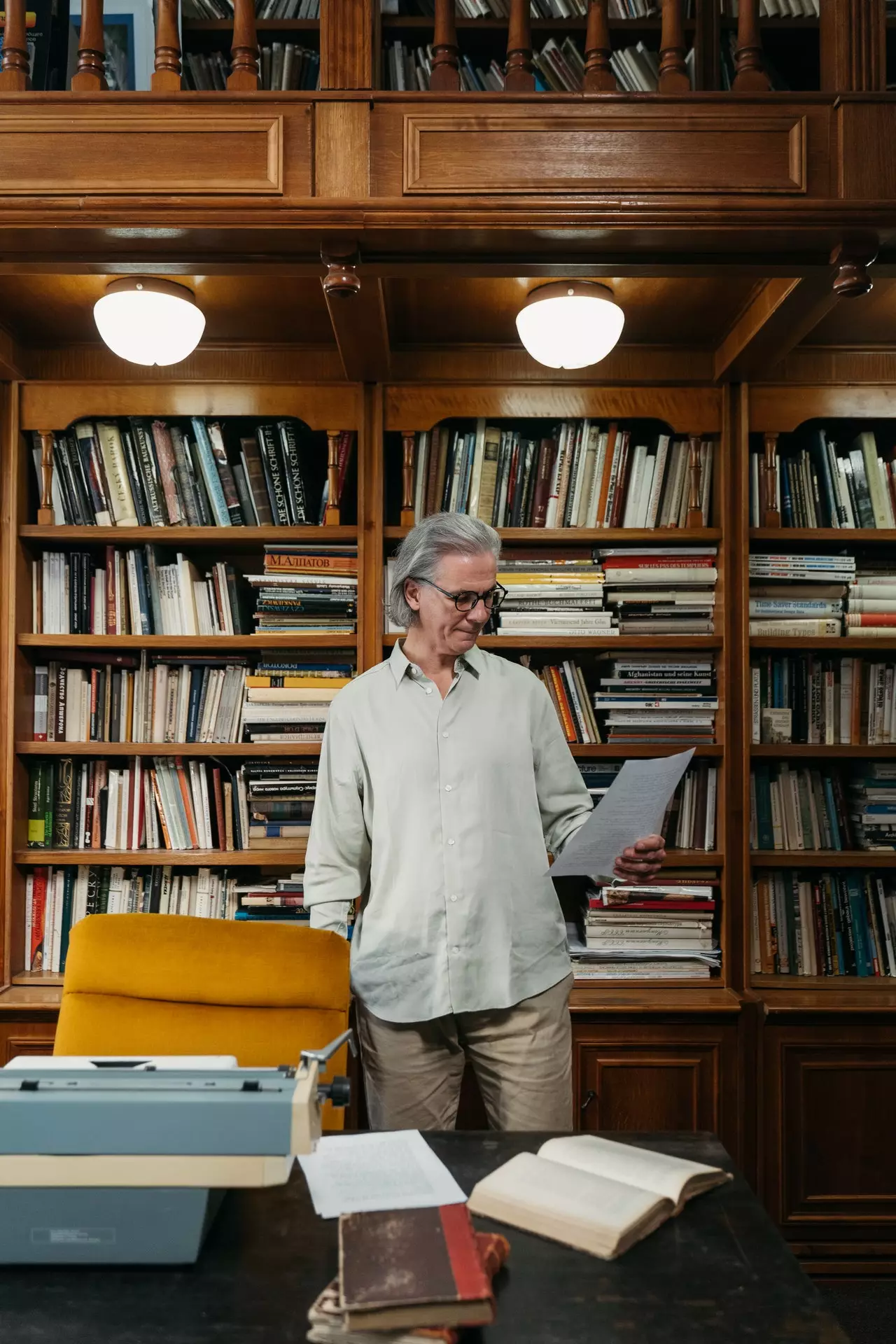 Un hombre mayor leyendo un libro de pie en una libreria